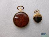 an image of two gold - plated pocket watches with a brown stone in the center