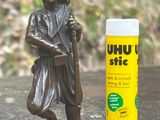 une statue représentant un homme tenant un savon à raser à côté d'un tube de savon à raser