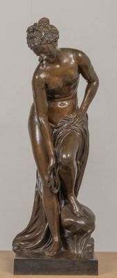 bronze statue of a man sitting on a rock with his hands on his knees