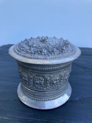 un plat ancien en argent contenant des raisins, posé sur une table noire