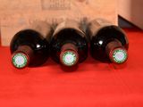 three bottles of wine are lined up on a red table
