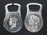 two silver coin shaped bottle openers on a black surface