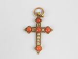une croix en or ornée de perles de corail sur fond blanc