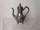 a silver tea pot sitting on a glass table