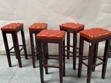 four red leather stools sitting on top of a tiled floor