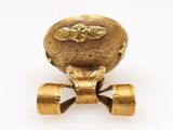 a gold vase with a flower on it on a white surface