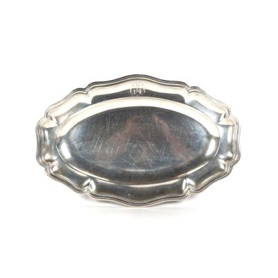 un plateau en argent muni d'une poignée en argent, posé sur une surface blanche