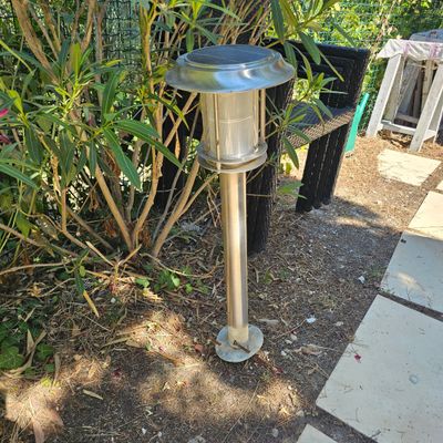 une lampe posée par terre près d'un buisson