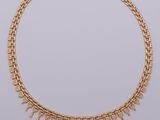 a gold necklace with fringes on a white background