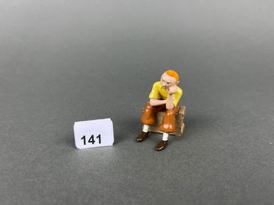 miniature figurine of a man sitting on a bench next to a sign