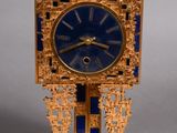 a gold clock with a blue face on a stand