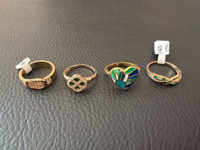 four rings with different designs on them sitting on a leather surface