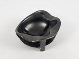 a black bowl with a black handle on a white surface