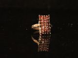 a gold ring with red stones on a black surface