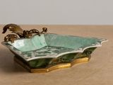 a green bowl with two birds on it on a table