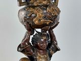 a statue of a man holding a bowl on his head