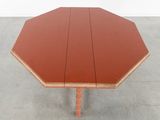 a red table with a wooden top on a cement floor