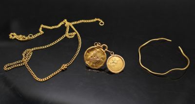 deux colliers en or et un bracelet posés sur un fond noir