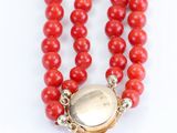 a close up of a red beaded necklace with a gold clasp