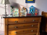 a wooden dresser in the corner of a room with a lamp on it