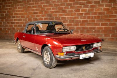 a red car that is parked in front of a brick wall