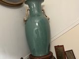 un vase vert posé sur une table à côté d'une chaise