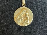 un gros plan sur un collier plaqué or orné de l'image d'une femme tenant un enfant dans ses bras