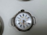 a silver pocket watch with roman numerals on the face
