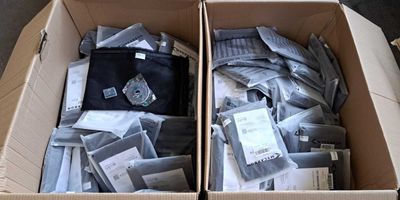 deux cartons remplis de vêtements posés l'un à côté de l'autre sur le sol