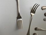 a lot of silver spoons, forks and spoons on the table