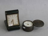 une petite horloge posée à côté d'une pièce de monnaie sur une table
