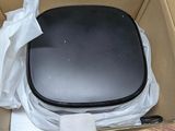 a black toilet in a cardboard box on a wooden floor