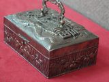 une vieille boîte en argent posée sur une table rouge