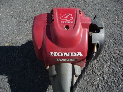 une photo d'une tondeuse à gazon Honda rouge posée par terre