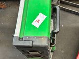 une machine verte posée par terre à côté d'une boîte rouge