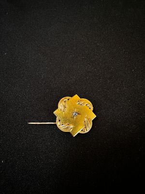 un gros plan d'une broche en forme de fleur dorée sur fond noir