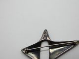 une broche en argent ornée d'une étoile, posée sur un fond blanc