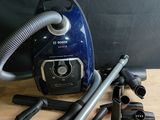 un aspirateur bleu et argent posé sur une table en bois