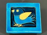un oiseau bleu et jaune posé sur une assiette bleue