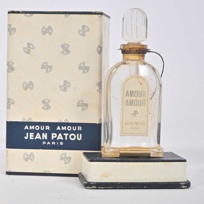 un flacon de parfum posé sur un livre, à côté d'une boîte