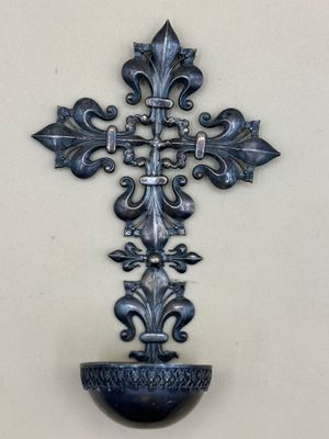 une croix en métal accrochée au mur, avec un vase