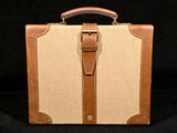 une valise marron et beige posée sur une surface noire