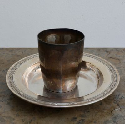 une tasse et une soucoupe en argent posées sur un plateau en argent