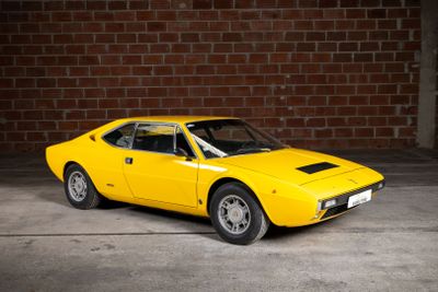 a yellow car that is parked in front of a brick wall