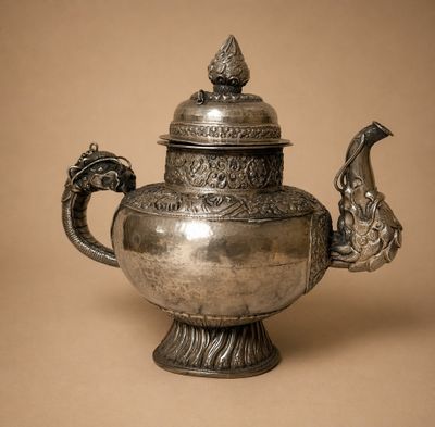 une vieille théière en argent surmontée d'un oiseau