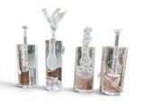 four glass bottles filled with different types of liquid and sand