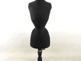 un mannequin noir posé sur un socle noir, devant un fond blanc