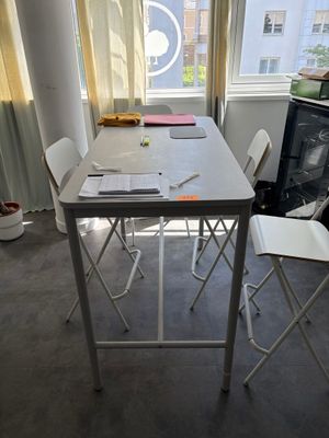 une table et des chaises blanches dans une pièce dotée d'une fenêtre