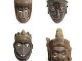 quatre masques en bois de formes et de tailles différentes sur un fond blanc