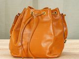 an orange bucket bag sitting on top of a wooden table